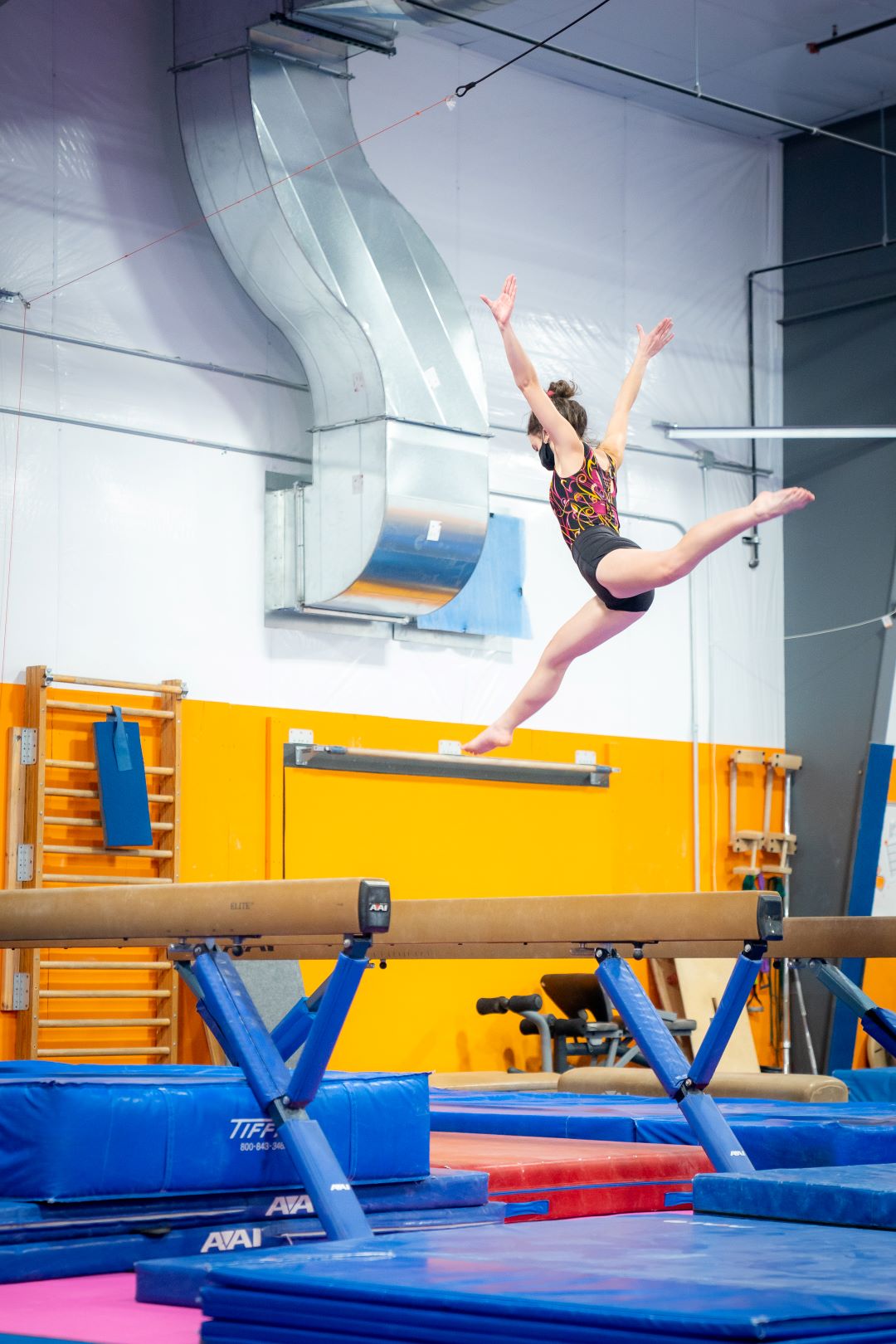 Gymnest on Beam doing a split jump